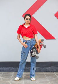 Portrait of smiling young woman standing against wall