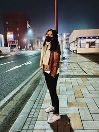 Full length of woman standing on footpath in city