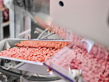 Contemporary pharmaceutical machine with piles of pink pills on conveyor placed in manufacturing laboratory