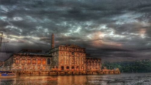 City at waterfront against cloudy sky