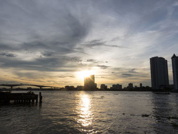 Scenic view of sea by buildings against sky during sunset