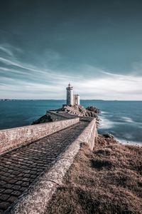 Lighthouse by sea against sky