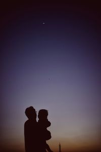 Silhouette man and woman standing against sky during sunset