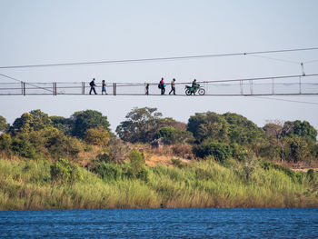 Group of people crossing zambezi river on footbridge in north of zambia, africa