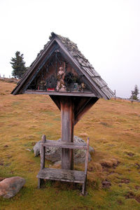 Old wooden house on field against clear sky