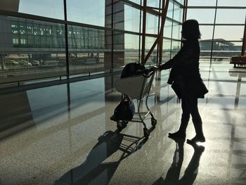 Woman holding luggage cart while in departure area