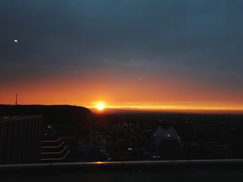 Illuminated cityscape against sky during sunset