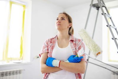 Portrait of young woman using mobile phone while standing at home