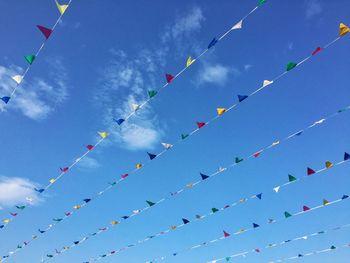 Low angle view of multi colored flags hanging against blue sky