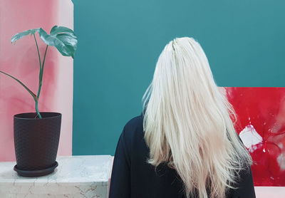 Rear view of woman on table against wall at home