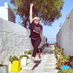 Woman jumping over footpath in sunny day