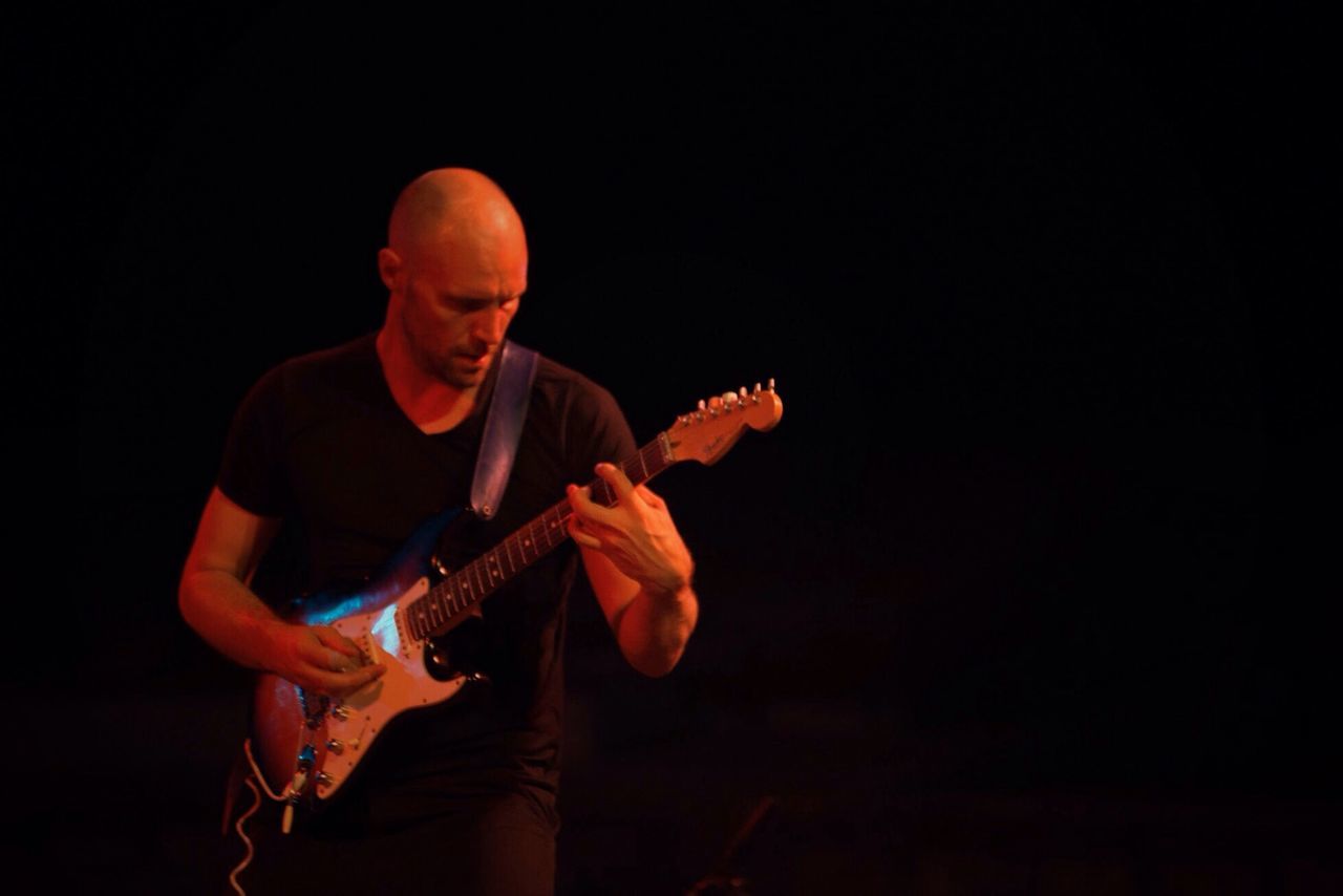 black background, music, performance, guitar, musician, playing, musical instrument, arts culture and entertainment, night, real people, one person, studio shot, plucking an instrument, electric guitar, men, indoors, adult, people