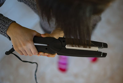 Woman ironing her hair with a hair iron.