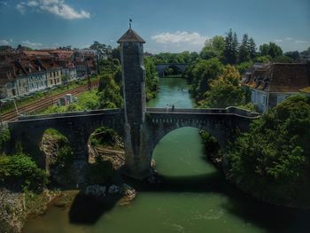 Bridge over river amidst buildings against sky