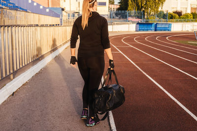 Rear view of woman walking with bag in stadium