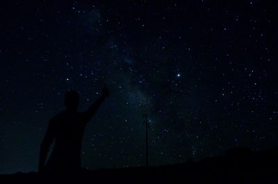 Silhouette man standing against sky at night