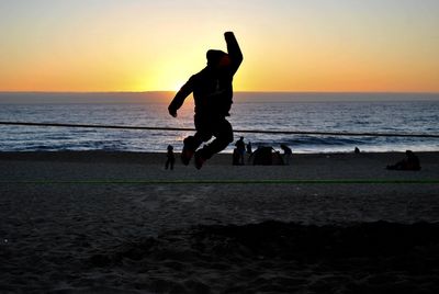 Silhouette of woman with dog on beach