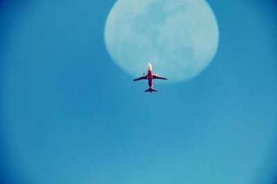 Low angle view of airplane against clear blue sky