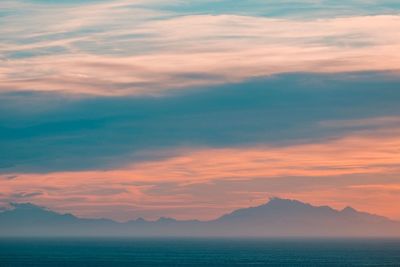 Scenic view of sea against dramatic sky during sunset