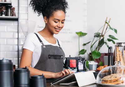 Side view of young woman using mobile phone at home