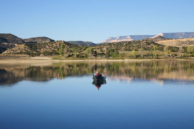 Man in lake against clear blue sky