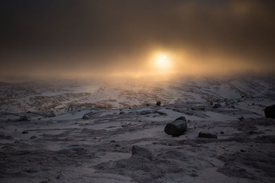 Scenic view of frozen landscape against sky during sunset