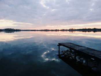 Pier on lake against cloudy sky