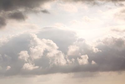 Low angle view of sunlight streaming through clouds