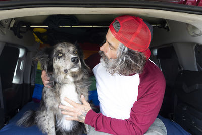 Gay man sitting with his black pet dog relaxing and enjoying the sunny day. person