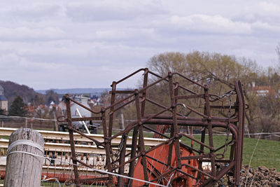 Metal fence on field against sky