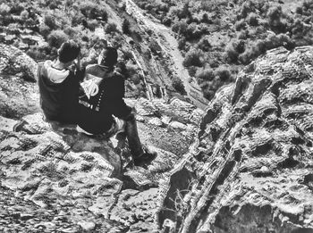 High angle view of couple sitting on rock