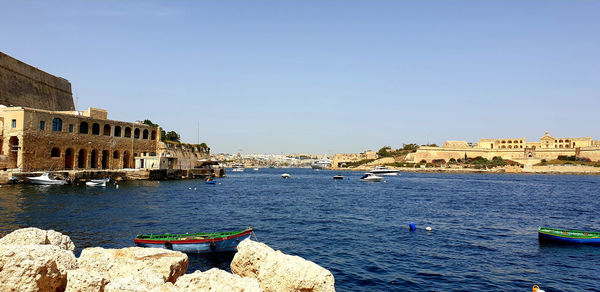 Boats in sea against buildings in city