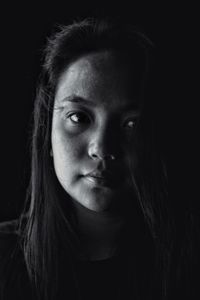 Close-up portrait of young woman against black background