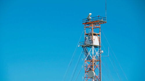 Low angle view of communications tower against clear blue sky