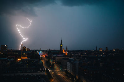 Lightning over cityscape against sky at night