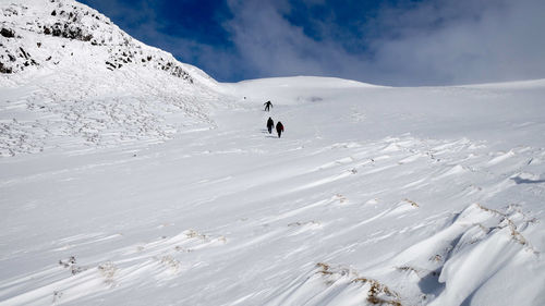 People walking on snowcapped mountain against sky