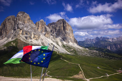 Scenic view of dolomites mountains against blue sky with flags