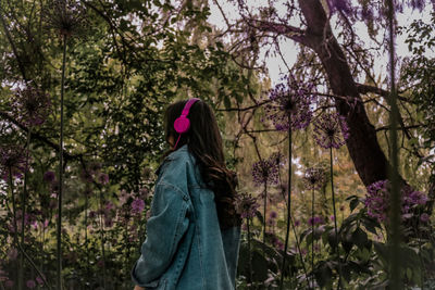 Rear view of woman standing on pink flowering plants