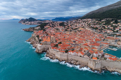 High angle view of townscape by sea against sky