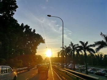 Cars on road against sky during sunset