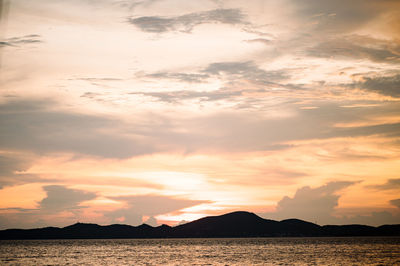 Scenic view of dramatic sky over silhouette mountains during sunset