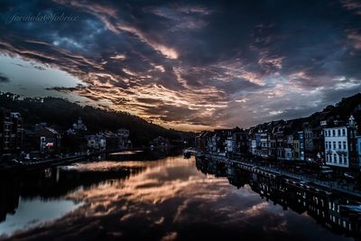 Reflection of illuminated buildings in river against sky