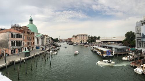 Boats in canal amidst buildings against sky