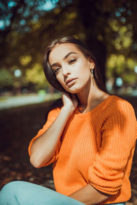 Young woman looking away while sitting on tree