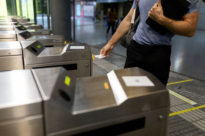 Man holding ticket at turnstile in subway