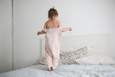 Happy funny girl toddler life style with a smile jumping on the bed, the concept 
