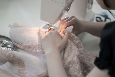 The girl sews a tweed skirt on a sewing machine, uses household equipment.