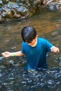 An asian boy feed and play with kelah fish in kelah sanctuary kenyir lake, terengganu.