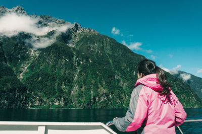 Rear view of woman looking at mountains against sky