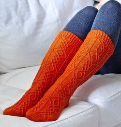Low section of woman wearing socks on sofa at home